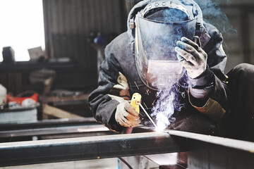 Male in face mask welds with welding