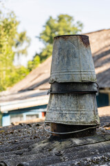 Chimney from old buckets on the roof of a rural house, closeup