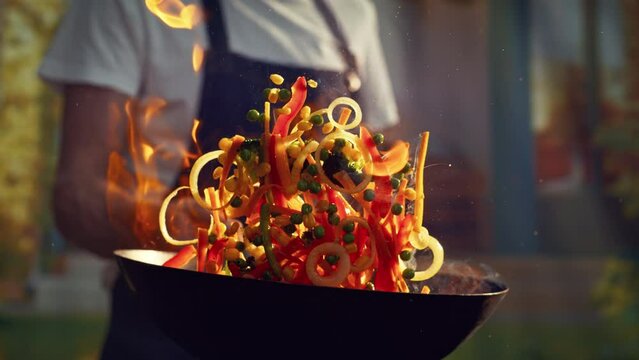 Close Up Super Slow Motion Footage. Chef Preparing Healthy Vegetables in a Restaurant. Cooking Flambe Style with Fire From Alcohol and Oil Making Final Touches to the Food