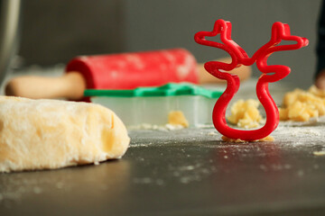 Red cookie cutter in shape of a deer with raw dough for Christmas cookies