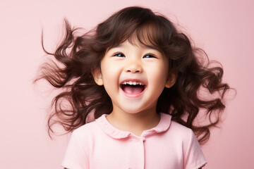 Healthy happy funny smiling face of a little Asian girl on a pink background