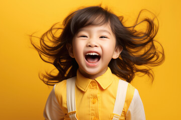 Happy smiling little Asian child girl on yellow background