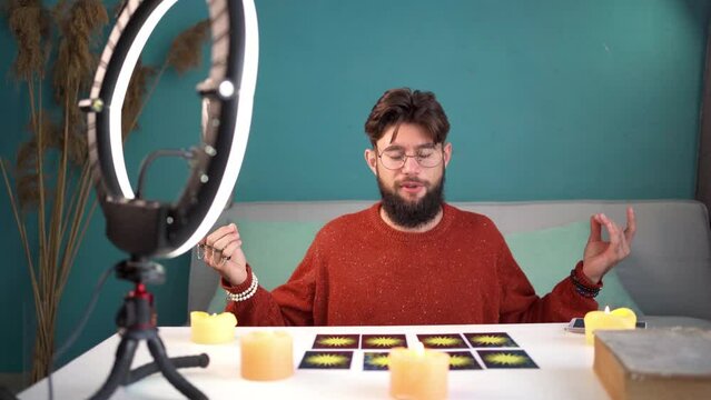 Peaceful fortune teller. Young bearded man meditating sitting with her eyes closed while after tarot card ritual.