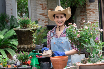 Asian woman gardener using biodegradable paper planting ornamental flowers in plant potted, gardening shop owner worker happy planting Lisianthus flowers mixing coaster paper and soil save the world