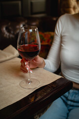 Hand holding a glass of red wine in a cozy bar setting