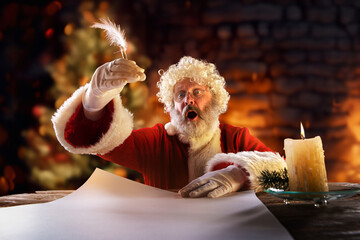 Senior emotional man, Santa Claus sitting at the table and writing letter with candle light....
