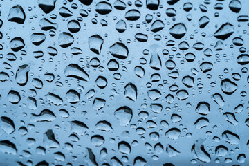 Raindrops cling to the car windshield, selective focus, soft focus.
