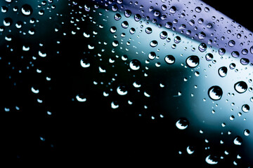 Raindrops cling to the car windshield, selective focus, soft focus.