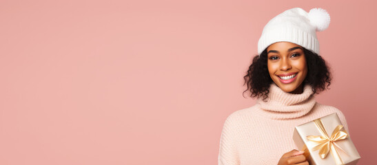 Pretty african american woman holding gift box in arms on pink background. Happy smiling girl with christmas present in her hands