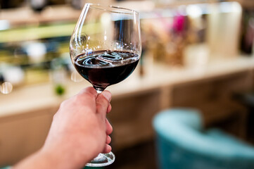 man hand holding a glass with red wine in a restaurant