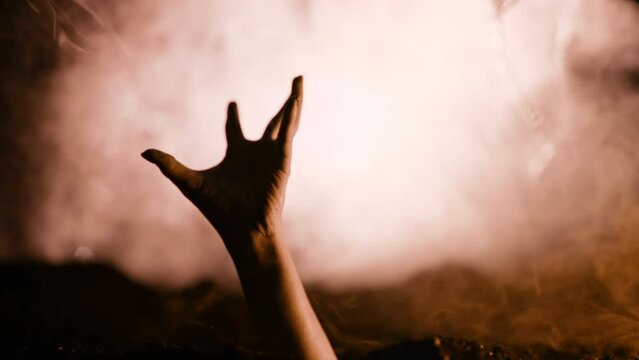 Terrible zombie hand climbs out grave. Creepy moment from undead life. Halloween