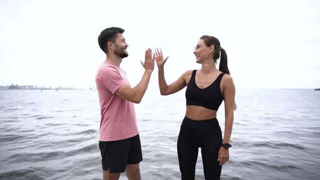 They beat each other's hands with their palms. Motivation two athletes are friends, a woman and a man training together. Break after fitness exercises and cardio.
