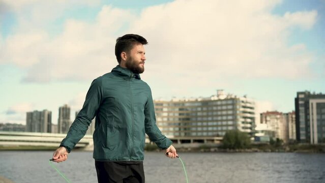 Portrait of a male athlete using a jump rope intensive cardio training jumping on the spot a man and fitness equipment on the background of the city.