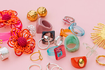 Colorful trendy bijouterie on pink background. Fashion silver, golden and plastic, acrylic and ceramic rings, bracelets and earrings. Stylish accessories. Women's jewelry.