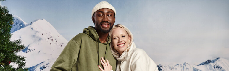 banner of happy woman hugging with african american boyfriend with mountain backdrop, winter fashion