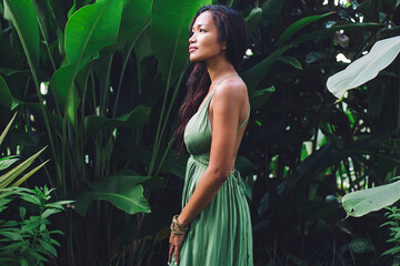 Romantic woman standing next to green tropical trees