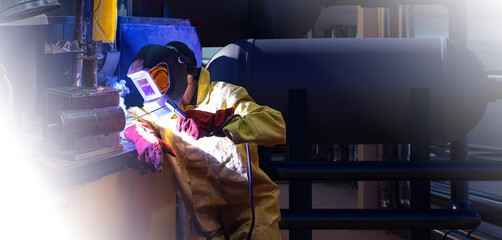 Man welder. Worker uses soldering machine. Human works as welder at company. Man welder wearing mask to protect eyes from sparks. Repair of production equipment with soldering machine. - Powered by Adobe