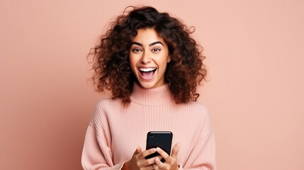 Fototapeta premium Portrait of a joyful young woman holding a mobile phone on a plain background