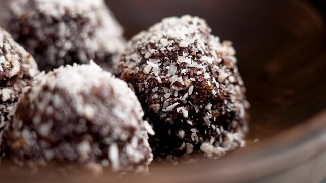 Chocolate coco balls in dark wooden bowl. Rotation. Macro shot