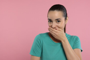 Embarrassed woman covering mouth on pink background. Space for text - Powered by Adobe