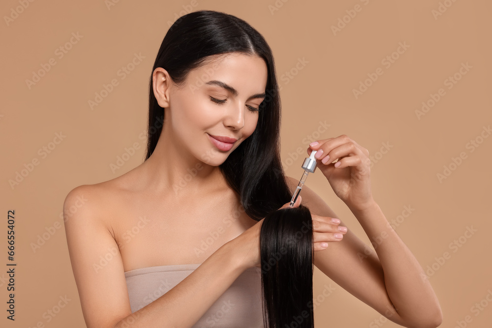 Poster Beautiful woman applying hair serum on beige background. Cosmetic product