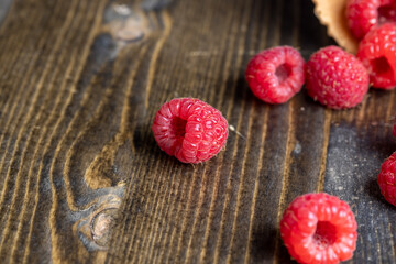 Red ripe raspberries with waffle cups on a black table