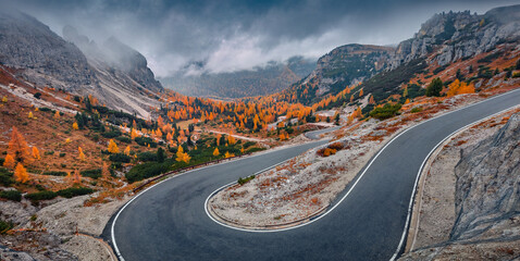 Misty autumn view of Tre Cime Di Lavaredo National Park with  winding road. Gloomy evening scene of Dolomite Alps, Auronzo Di Cadore location, Italy, Europe. Beauty of nature concept background. - obrazy, fototapety, plakaty