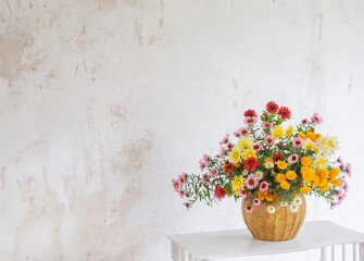 Fototapeta na wymiar bouquet of colorful chrysanthemums in vase on background white old wall