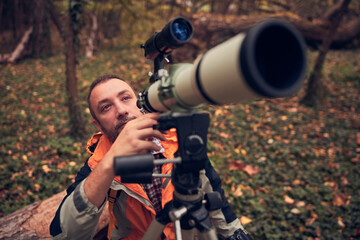 man using telescope for bird and animal watching in nature.