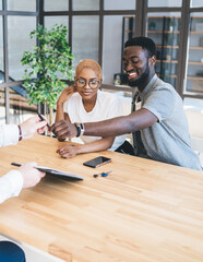 Joyful black couple making deal with realtor
