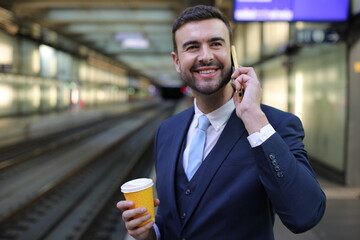 Handsome businessman making a phone call from train station 
