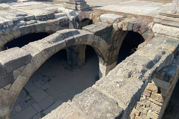 Ruins ancient city stone temple in İzmir, top arches, keystones, columns, torso statue, corridors, rooms, running fresh water between high stone wall