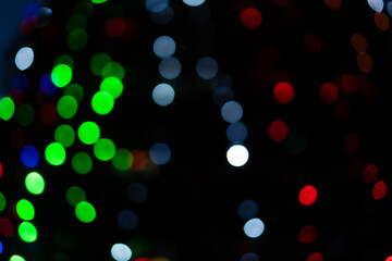 Bokeh, colorful bright green, red, blue lights blurred on the street. Unfocused sparkling lights on the street