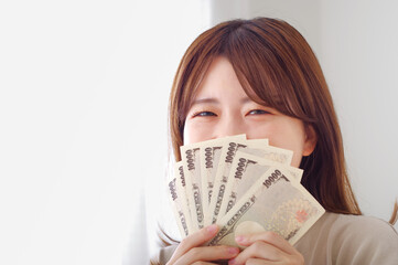 笑顔で嬉しそうにお金を持つ若い女性