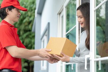 Happy smiling woman receives boxes parcel from courier in front house. Delivery man send deliver...