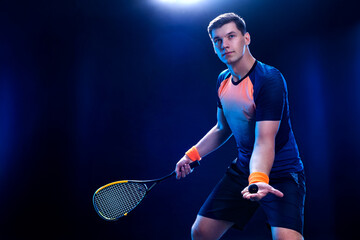 Squash player on a squash court with racket. Man athlete with racket on court with neon colors....