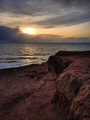 sunrise in the ocean with blue and orange sky with dramatic clouds seen from the cliff, at Pipa beach - Brazil