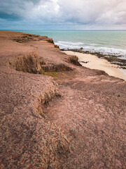 sunrise in the ocean with blue and orange sky with dramatic clouds seen from the cliff, at Pipa beach - Brazil