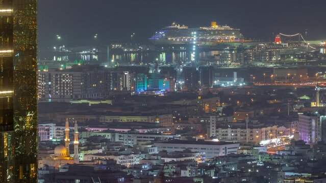 Aerial view of apartment houses and villas in Dubai city near downtown night timelapse. Sea port and construction site on a background. United Arab Emirates