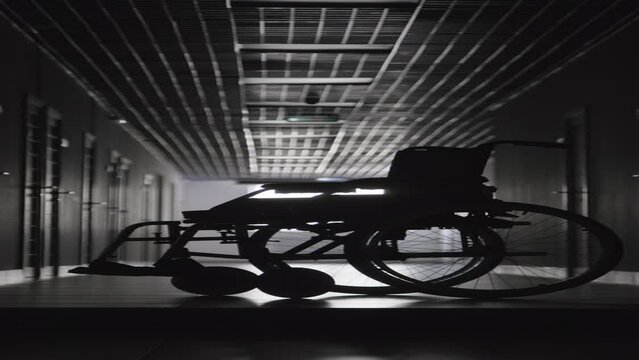 Vertical full black and white shot of wheelchair standing in center of hospitals hallway
