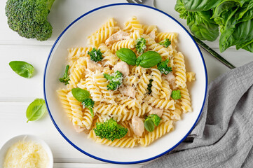Delicious broccoli and chicken fusilli pasta with parmesan cheese and fresh basil in a bowl on a...
