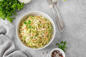 Traditional cole slaw salad in a bowl on a gray concrete background. Salad with cabbage, carrot and...