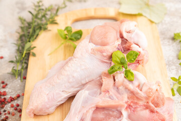 Raw turkey wing on a wooden cutting board on a brown concrete background. Side view, selective focus