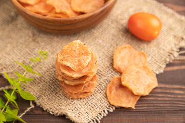 Slices of dehydrated salted meat chips on brown wooden, side view, selective focus