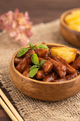 Tteokbokki or Topokki, fried rice cake stick, on brown wooden, side view, selective focus
