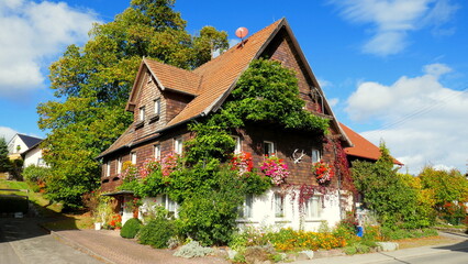 Fototapeta na wymiar traditionelles altes Wohnhaus mit Blumenschmuck im Herbst in Neuweiler im Nordschwarzwald