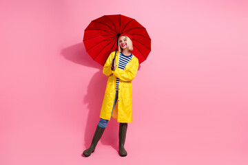 Full length photo of cute shiny woman dressed rain coat walking under parasol empty space isolated...