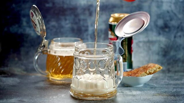 Pouring beer into a beer mug on a dark background. Slow motion. The slow motion of pouring beer into a glass placed on the table.