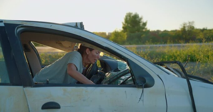 A woman sits in a wrecked car after a car accident and tries to get out of the wrecked car in a state of shock and stress