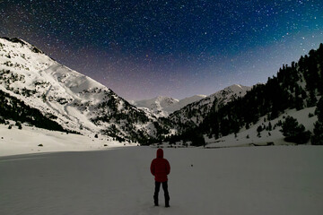 hiker stargazing in a snowy mountain landscape